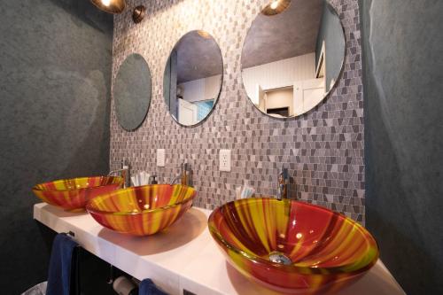 three sinks in a bathroom with three mirrors at THE BEEHIVE AIOI in Otaru
