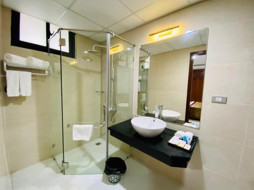 ein Bad mit einem Waschbecken und einer Glasdusche in der Unterkunft Kim Thai Hotel in Thái Nguyên