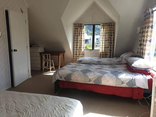 a bedroom with two beds and a window at Hosts on the Coast Dad's Place in Whangamata