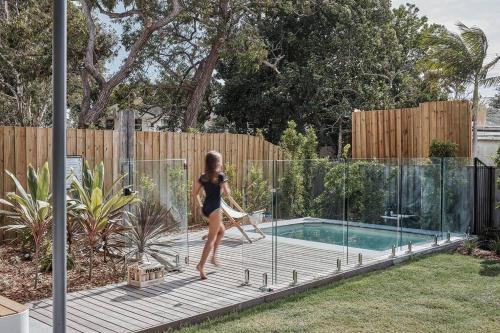 a woman is standing near a swimming pool at Sanctuary Spaces - Lomani Eleven in Byron Bay