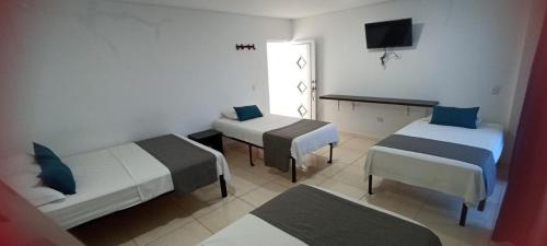 a hotel room with two beds and a television at Hotel La Inmaculada in Soledad