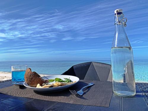 a table with a plate of food and a bottle of water at Niru Isle Maldives in Gaafaru