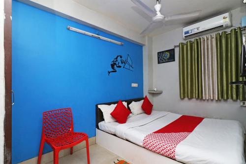 a bedroom with a bed and a red chair at Hotel O Sher E Bengal in Durgāpur