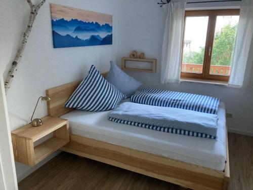 a bedroom with a bed with two pillows and a window at TraunZeit in Siegsdorf