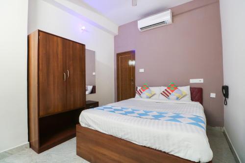 a bedroom with a large bed with a wooden cabinet at Super Hotel O Adri Hotels in Kolkata