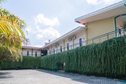 a building with a tall green hedge in front of it at RedDoorz Plus Syariah At Lotus Hotel Bojonegoro in Bojonegoro