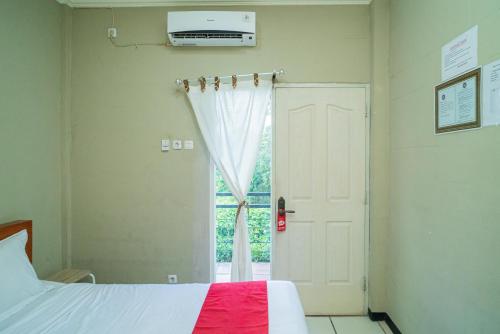 a bedroom with a bed and a window at RedDoorz Plus Syariah At Lotus Hotel Bojonegoro in Bojonegoro