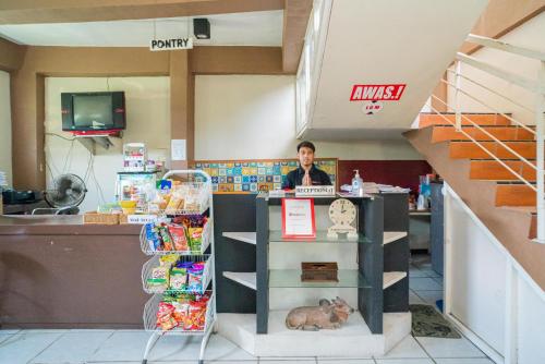 a man standing behind a counter in a store at RedDoorz Plus Syariah At Lotus Hotel Bojonegoro in Bojonegoro