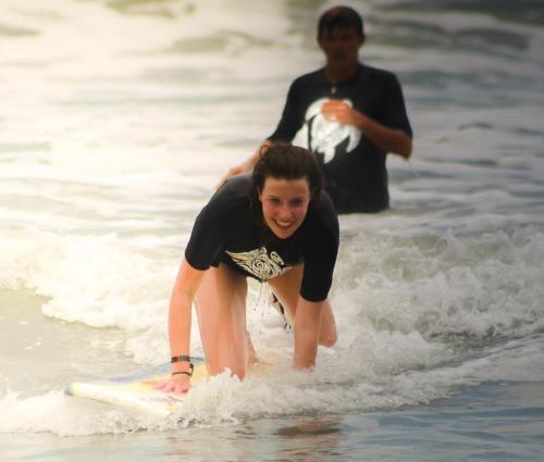 a young person riding a surfboard in the water at Hotel Maya Jade in Monterrico