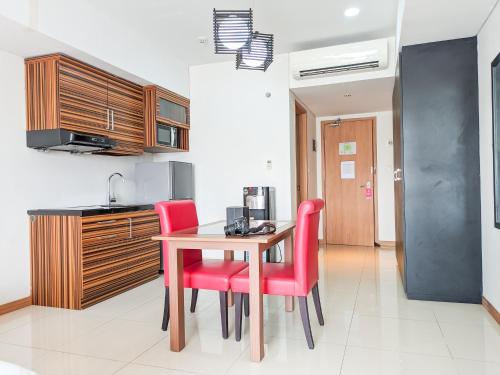 a kitchen with a wooden table and red chairs at Sakura Park Hotel & Residence in Cikarang
