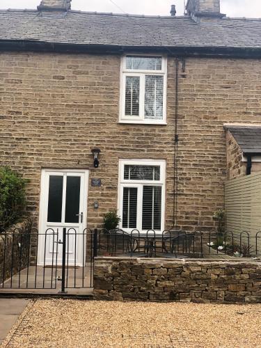 a brick house with a white door and windows at Marina View cottage in Furness Vale