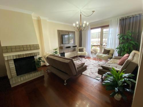 a living room with a couch and a fireplace at BELÍSSIMO apt ALTO DA SERRA no centro de Gramado in Gramado