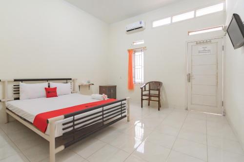 um quarto com uma cama, uma cadeira e uma porta em RedDoorz Syariah near Tugu Pandanwangi Cianjur 