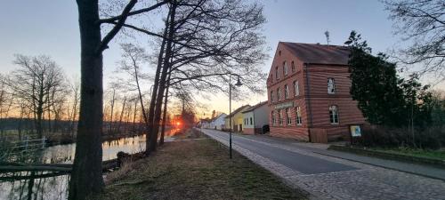 an empty street with a brick building next to a river at Hug&Dim im Gasthaus am Finowkanal in Wandlitz