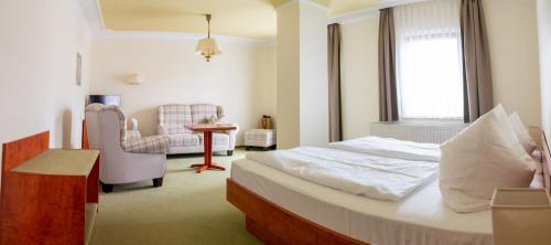 a hotel room with a bed and a chair at Landhotel Biberburg in Bad Liebenwerda