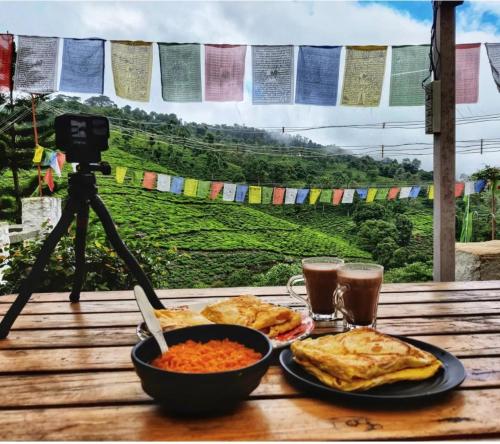 a table with a plate of food and a camera at The Door to Nirvana Backpackers Hostel Kotagiri in Kotagiri