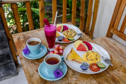 a table with two plates of food and two cups of coffee at The Box House in Nusa Penida