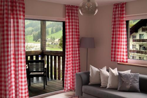a living room with red and white curtains and a couch at Chalet Alte Post in Schwarzsee