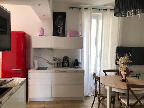 a kitchen with a table and a red refrigerator at Très bel appart meublé classé 3 étoiles entièrement rénové et climatisé 50 m centre et 150 m plage in LʼÎle-Rousse