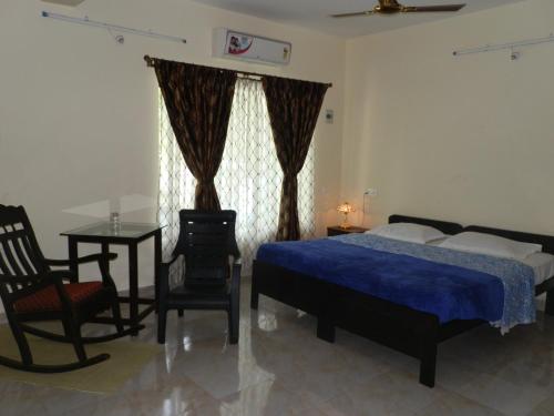 a bedroom with a bed and a table and chairs at Aldrin Guest House in Palolem