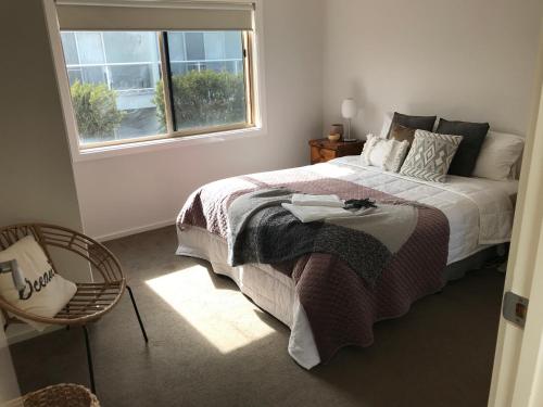 Inverloch Cabins & Apartments في إينفيرلوك: غرفة نوم بسرير ونافذة وكرسي
