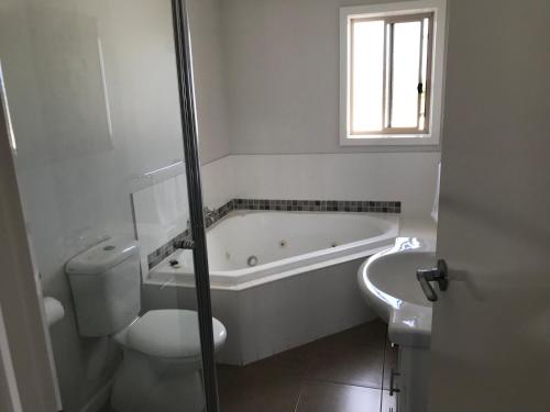 Inverloch Cabins & Apartments في إينفيرلوك: حمام أبيض مع حوض ومرحاض