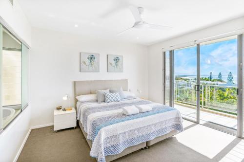 a white bedroom with a bed and a large window at Rainbow Sea Resort in Rainbow Beach
