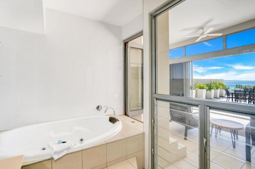 a bath tub in a bathroom with a view of the ocean at Rainbow Sea Resort in Rainbow Beach