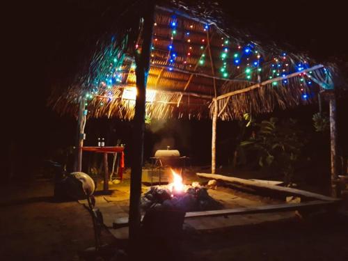 a bonfire in front of a hut with christmas lights at Alma Del Rio Eco-Comfort on the water in San Ignacio