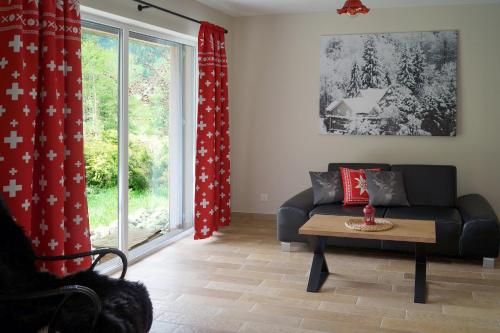 a living room with a couch and a table and a window at Chalet Alte Post in Schwarzsee
