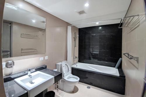 a bathroom with a sink and a toilet and a tub at Sakura Park Hotel & Residence in Cikarang