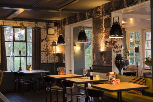a restaurant with wooden tables and chairs and windows at Café Brasserie Het Heerenhuis in Het Kalf