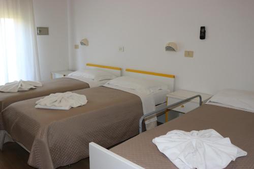 three beds in a room with towels on them at Hotel Neps in Lido di Jesolo
