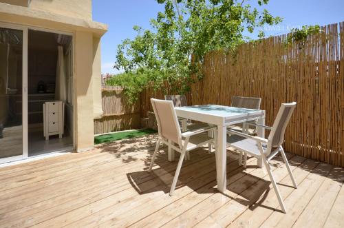 a white table and chairs on a wooden deck at Yalarent Hawaii Complex Boutique & Garden Hotel Apartments Eilat in Eilat