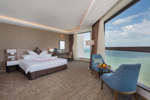 a hotel room with a bed and a large window at Asteria Comodo Nha Trang Hotel in Nha Trang