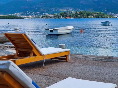 a lounge chair and a boat on a body of water at Luxury Apartment Maja in Tivat