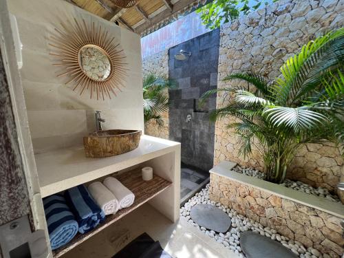a bathroom with a shower with a sink and a plant at Santana Villas Bingin in Uluwatu