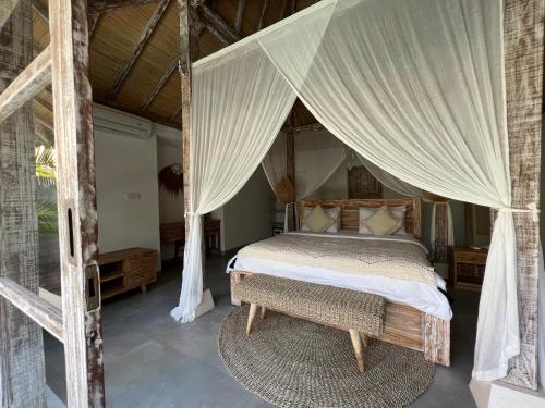 烏魯瓦圖的住宿－Santana Villas Bingin，一间卧室配有一张带天蓬的床