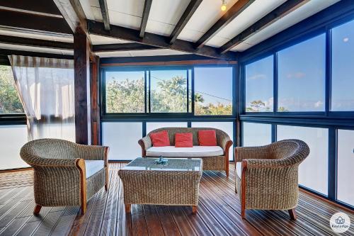 a living room with chairs and a table and windows at Kaz Bois Blanc, classée 3 étoiles - Vue mer - Les Avirons in Les Avirons