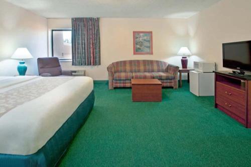 a hotel room with a bed and a couch and a television at Norwood Inn & Suites Indianapolis East Post Drive in Indianapolis