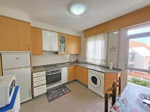uma cozinha com armários de madeira e uma máquina de lavar e secar roupa em Apartamentos Portonovo 3000 em Portonovo