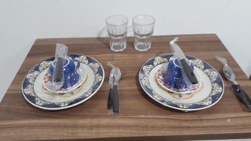 dois pratos com garfos e facas numa mesa de madeira em Maravilhoso FLAT 201 próximo Shopping Partage em Campina Grande