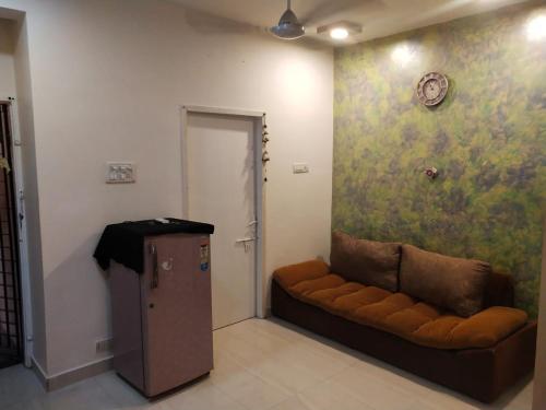 a living room with a couch and a clock on a wall at Pearl Service Apartment in Chennai