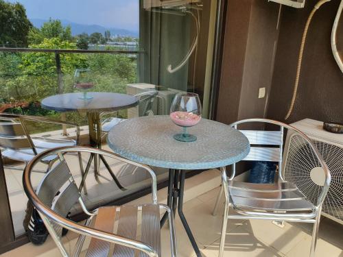 2 Tische und Stühle auf einem Balkon mit Fenster in der Unterkunft New Apartment at a Great Location in Blagoewgrad