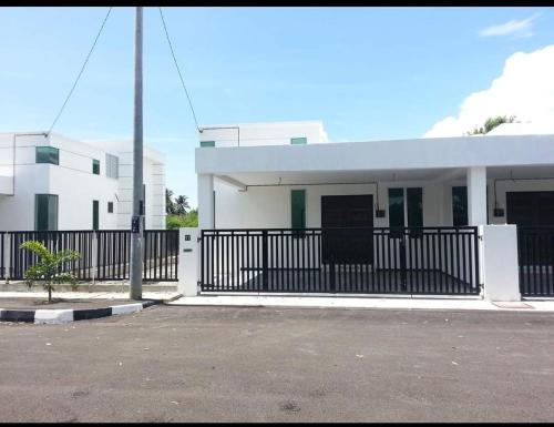 a white building with a black fence in front of it at Noorsyah Homestay Stadium Utama in Kangar