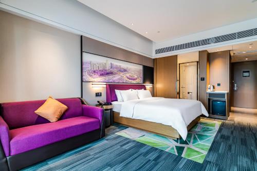 une chambre d'hôtel avec un lit et un canapé violet dans l'établissement 敏卓酒店Mentor Hotel, à Foshan