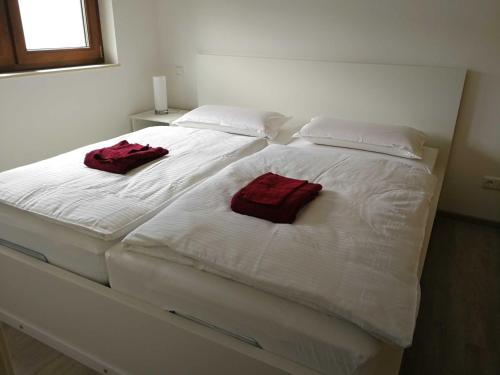 ein weißes Bett mit zwei roten Handtüchern drauf in der Unterkunft Villa Peony in Muhlheim am Main