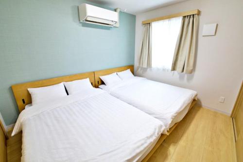 two beds in a small room with a window at メイスン倶楽部 安里 4F in Naha