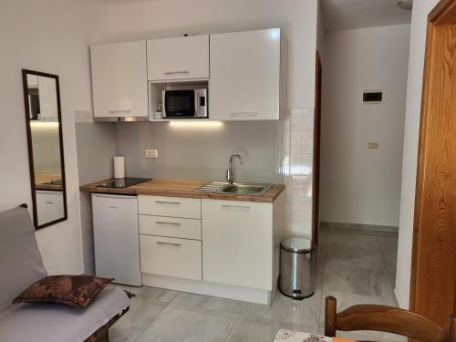 una cocina con armarios blancos y fregadero en Apartments Jobst, en Vela Luka