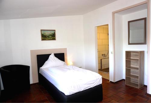 1 Schlafzimmer mit einem weißen Bett und einem Badezimmer in der Unterkunft Dreikausens Landgasthaus Wildhof in Cleeberg